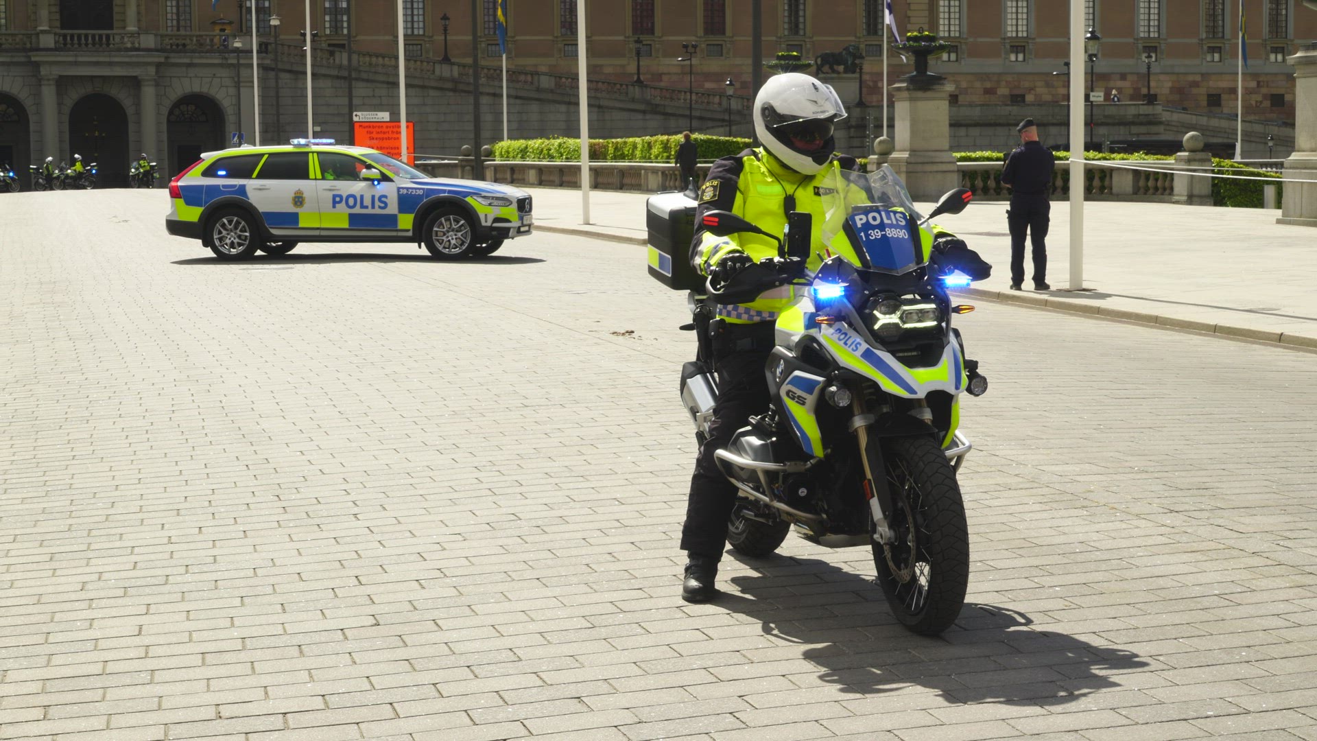 policeman on motorcycle in street - drives away - police car in background
