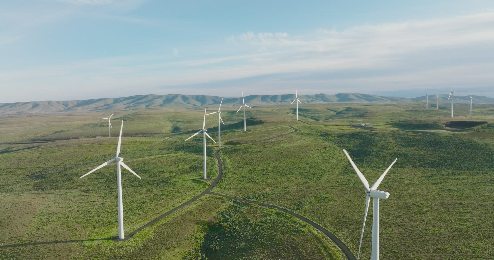 Wide static aerial shot of wind turbine farm