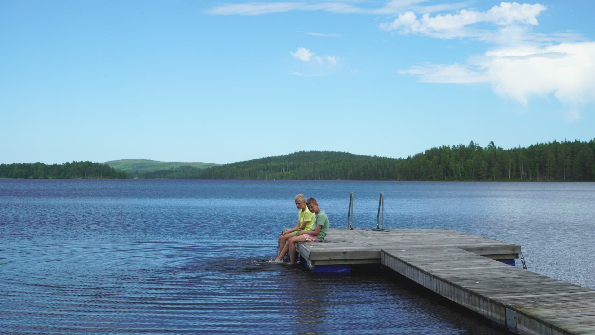 boys relaxing on jetty in lake - värmland