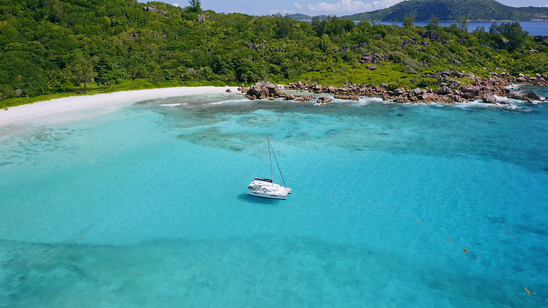 Aerial 4k drone circle footage of white yacht in crystal clear turquoise lagoon water in front of go