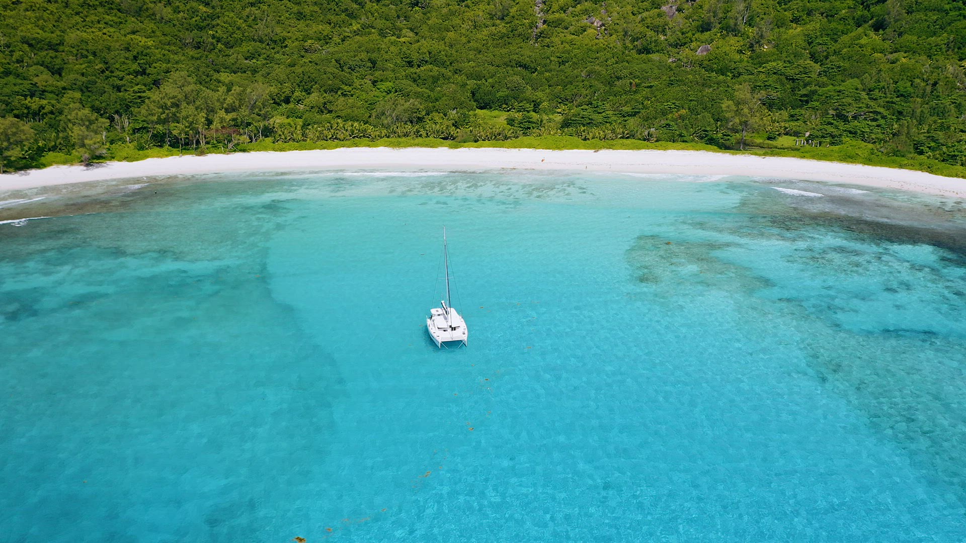 Seychelles, La Digue Island. Aerial footage of lonely luxury white catamaran yacht in turquoise clea