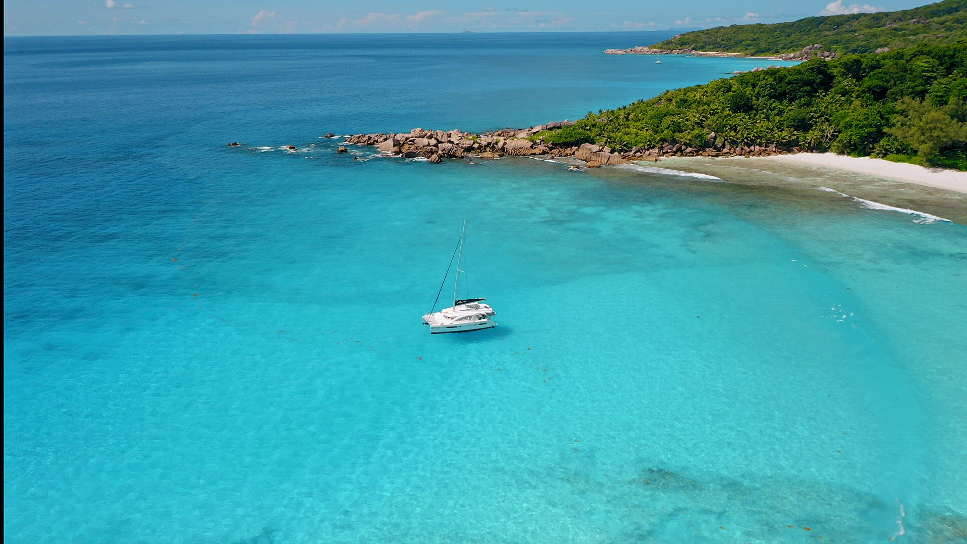 Seychelles, La Digue Island. Drone circle footage of white yachts in calm turquoise lagoon ocean wat