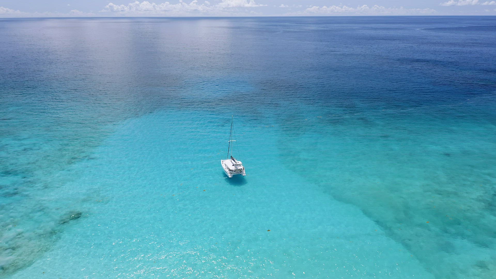 Aerial view of lonely luxury catamaran yacht in crystal clear blue lagoon with reflected light. La D