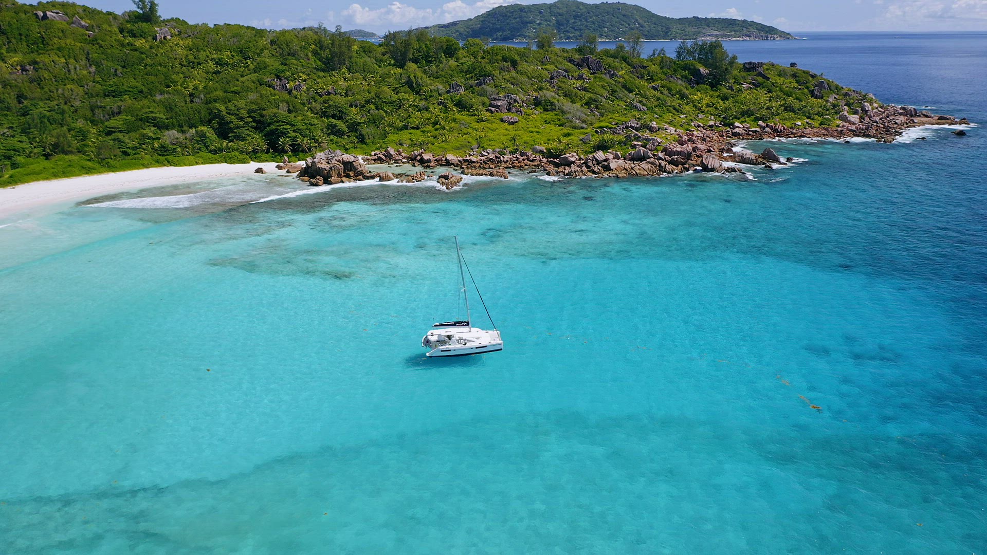 Aerial view of lonely luxury catamaran yacht in blue lagoon. La Digue island, Seychelles