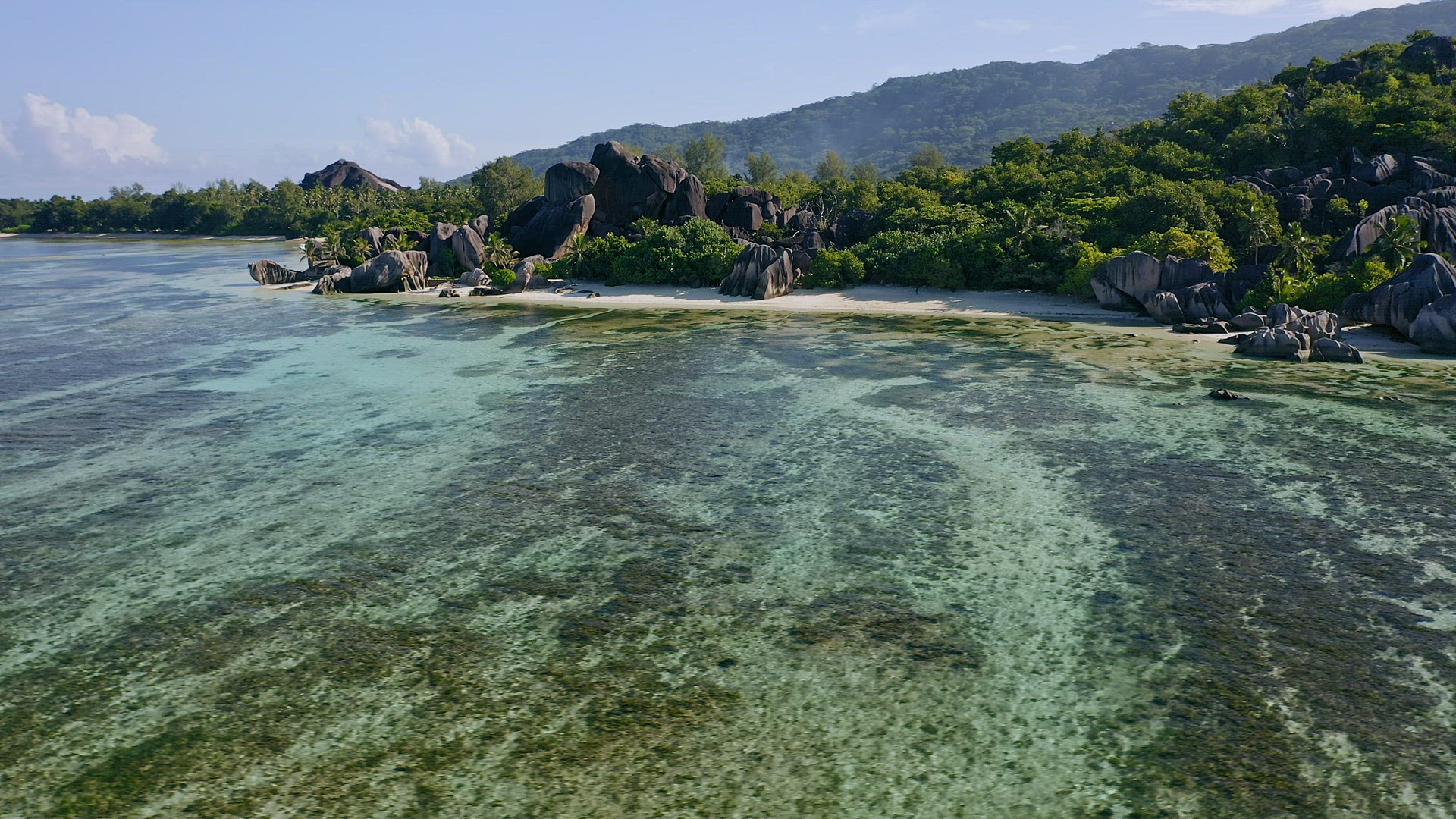 Aerial footage circling around granite boulders on famous Anse Source d'Argent tropical beach at sun