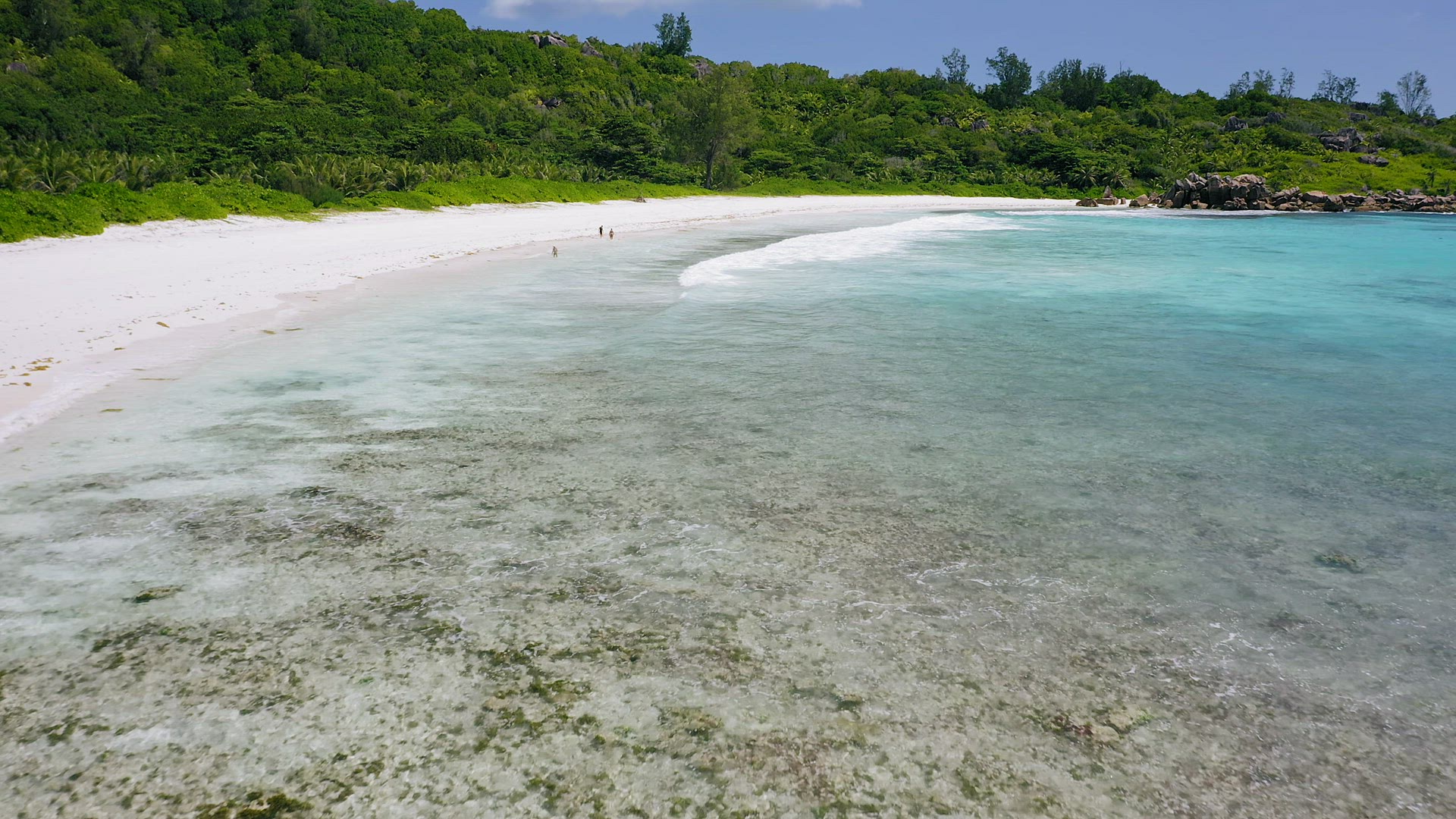 Aerial low altitude fly footage over tropical white sand beach and turquoise water lagoon with long 
