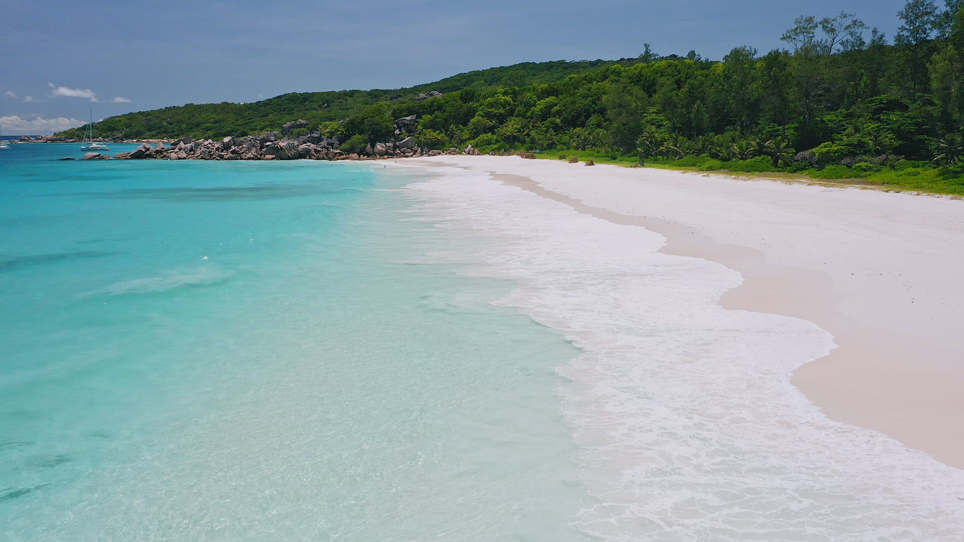 Low flight above transparent azure ocean water, white waves reaching exotic paradise sand beach. Sum
