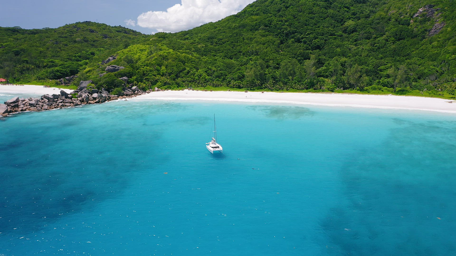 Aerial view footage of luxury catamaran yacht moored in clear turquoise blue ocean water of Petite A