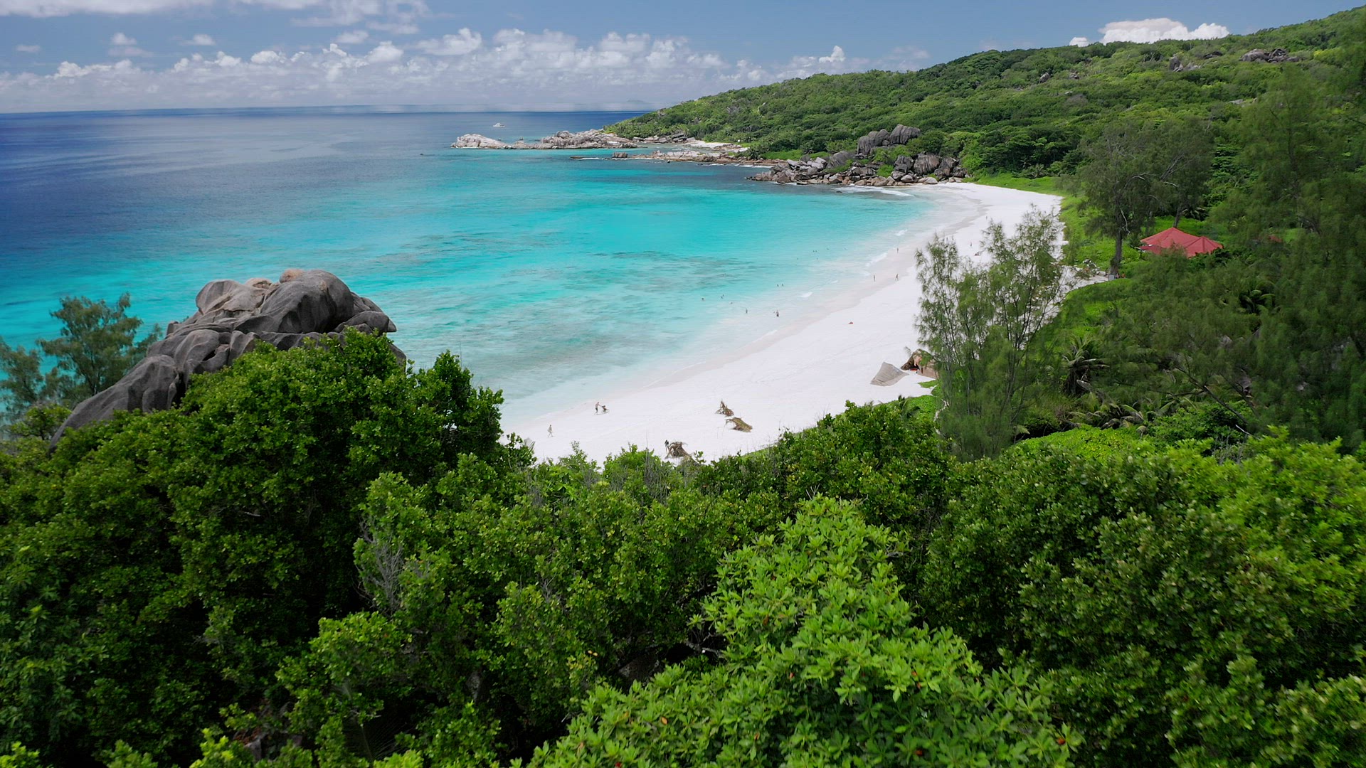 Aerial fly over white sand Grand Anse beach. Crystal clear turquoise blue ocean lagoon. La Digue isl