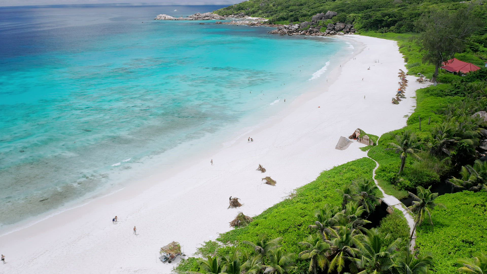 Aerial fly over white sand Grand Anse beach. Crystal clear turquoise blue ocean lagoon. La Digue isl