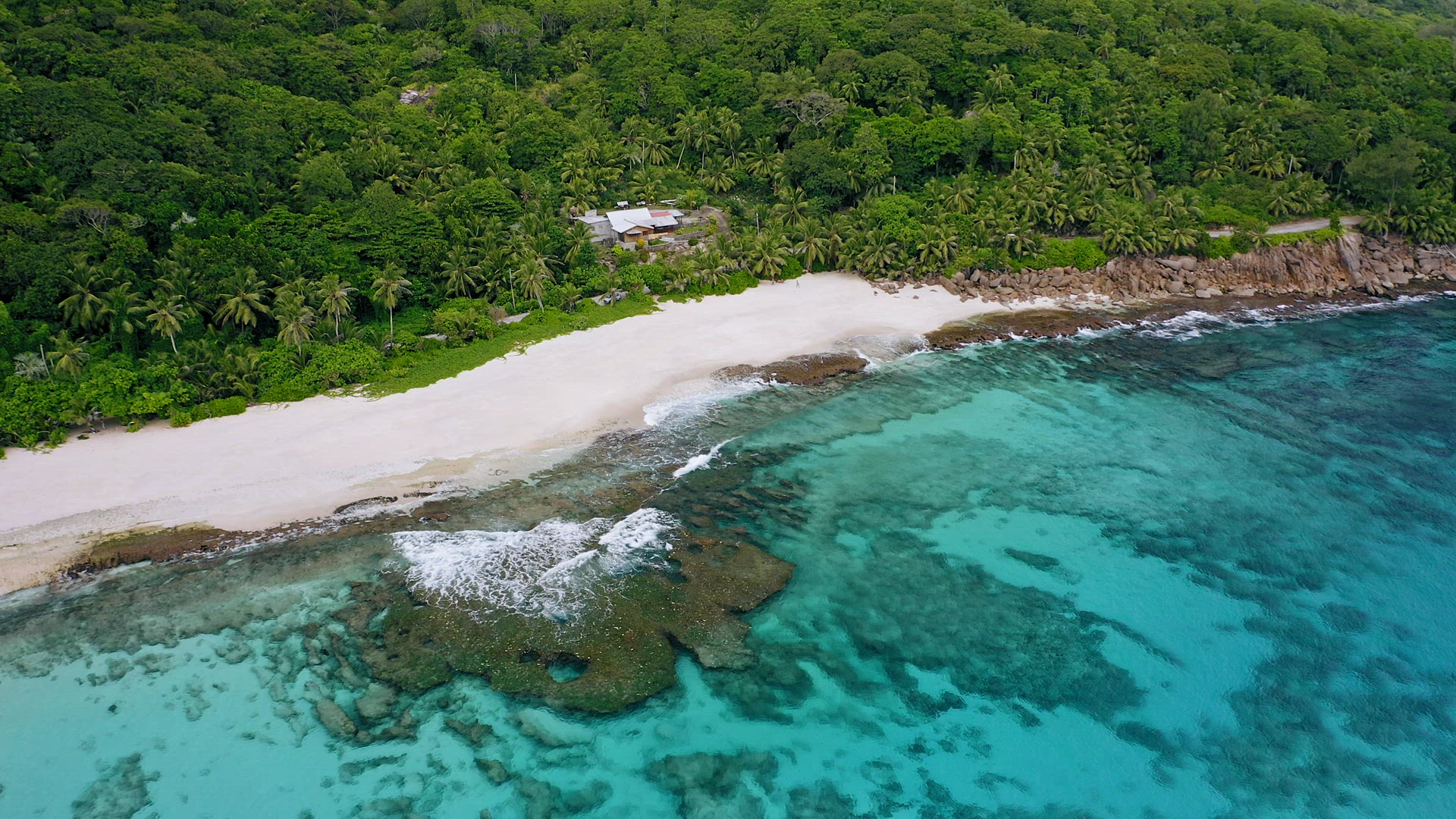 Aerial footage of tropical beach with white sand beach and crystal clear water and coral reef at Mah