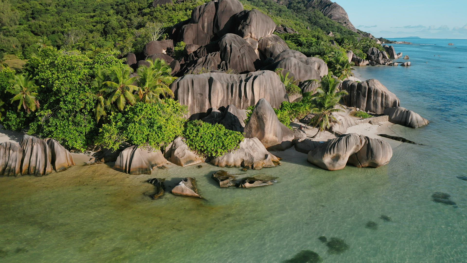 Aerial footage of famous Anse Source d'Argent tropical beach at sunny day bright light with shallow 