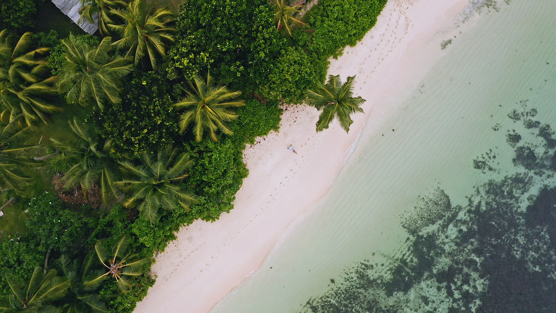 4k aerial view vertical spinning move up footage from girl sitting on a white sand beach. Surrounded