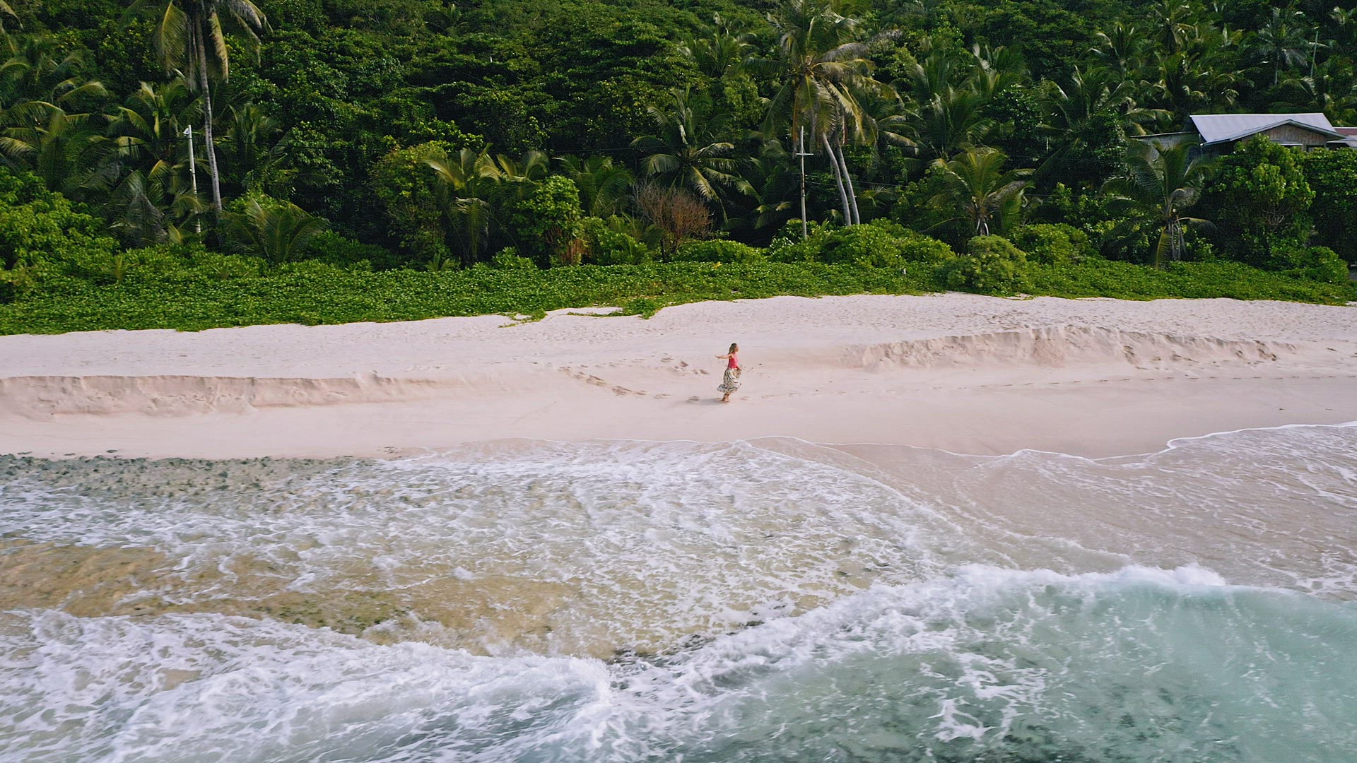 Aerial footage of young tanned woman running on sandy tropical beach with ocean waves rolling. Mahe 