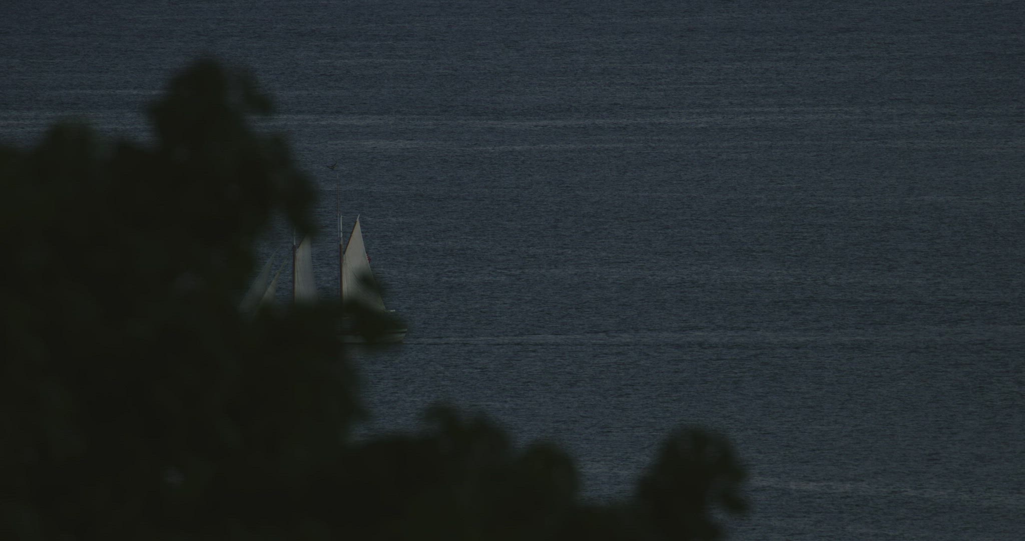 Boat sailing through bay at dusk