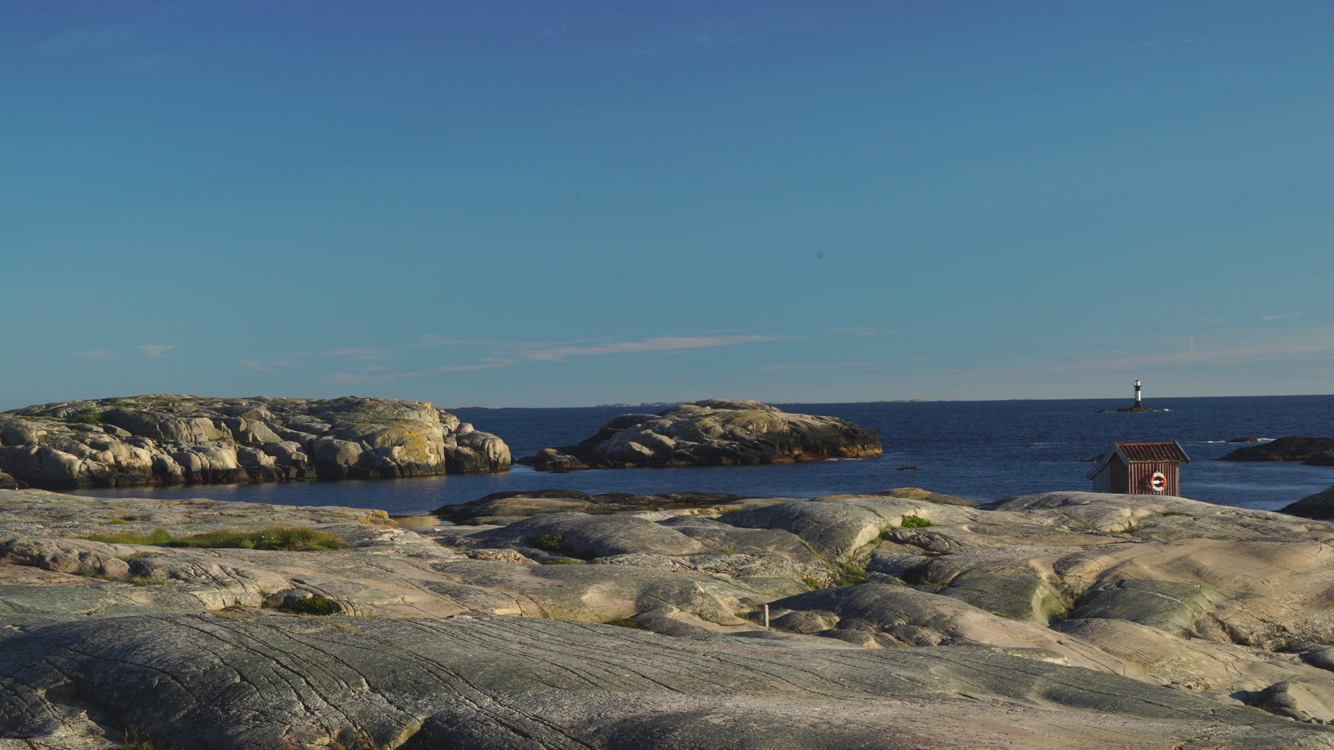 view over cliffs and sparse landscape in bohuslän - small red house - lighthouse