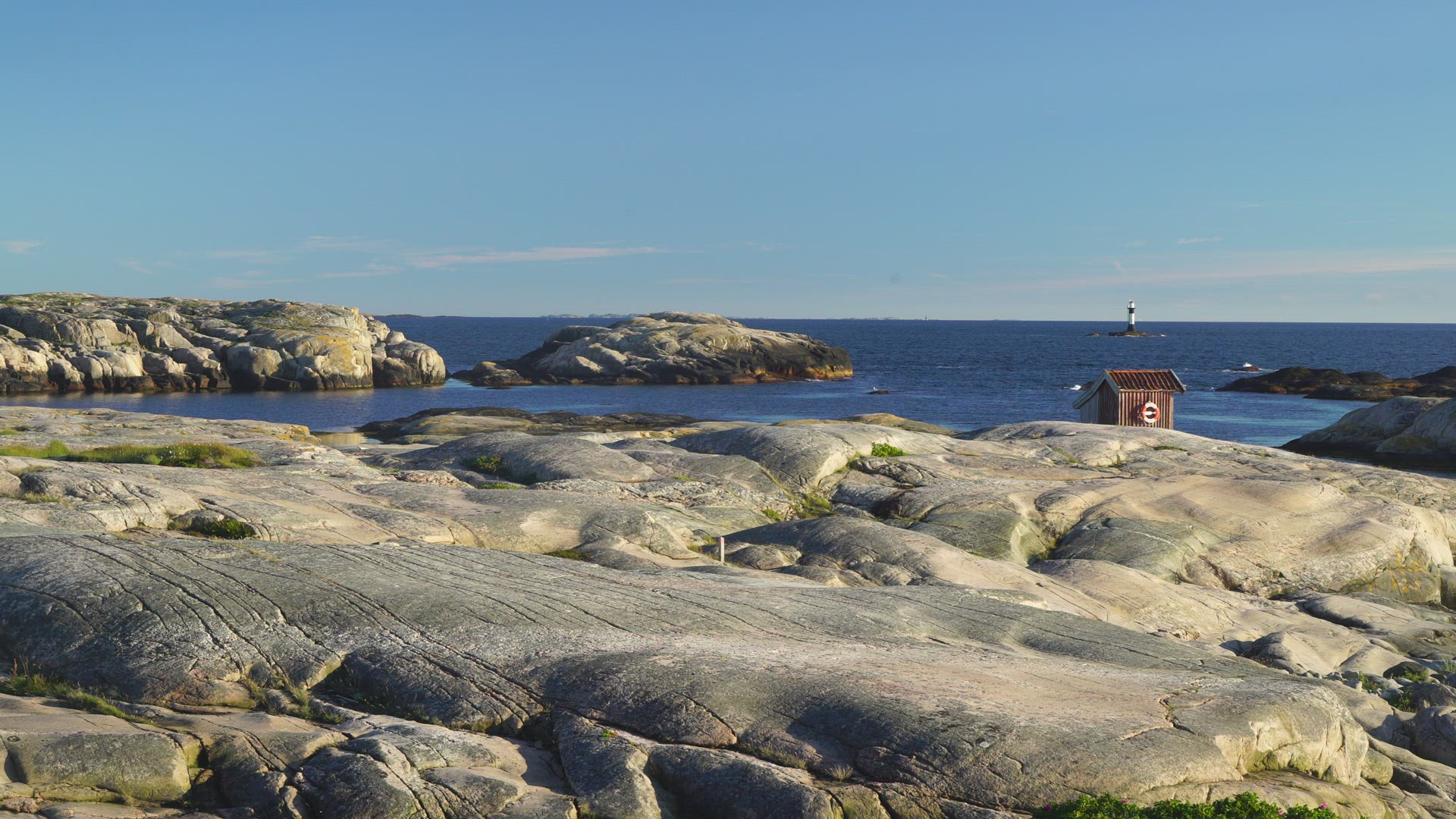 view landscape in bohuslän - cliffs - sea - small red house - lighthouse in background