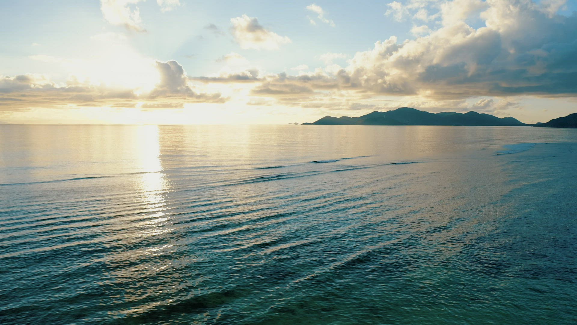 Sunset 4k footage over calm sea with tropical island silhouette on horizon. Flying the drone at low 