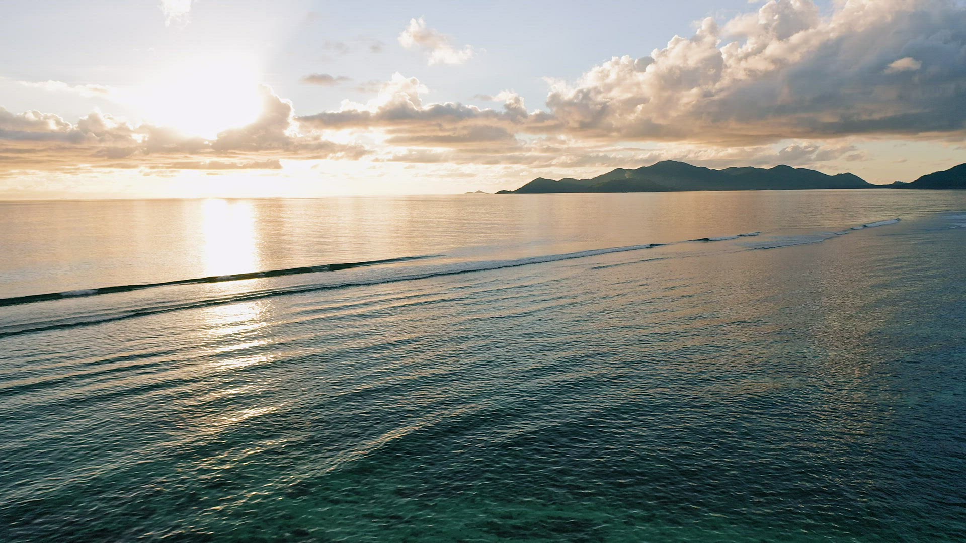 Aerial 4K footage of sunset and ocean waves at tropical island. Flying the drone at low altitude abo