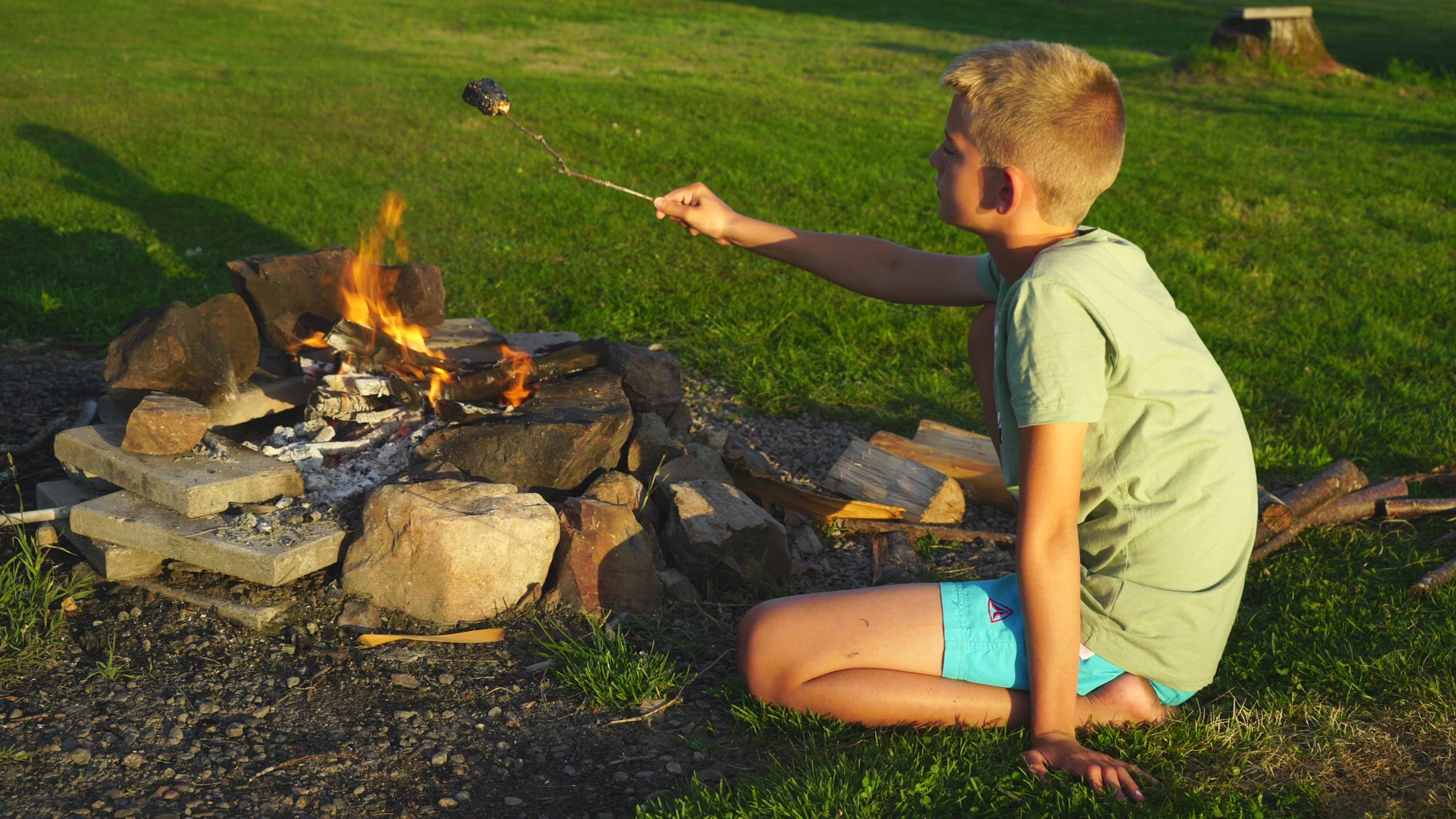 boy sitting at outdoor open fire - grilling marshmallow - burnt