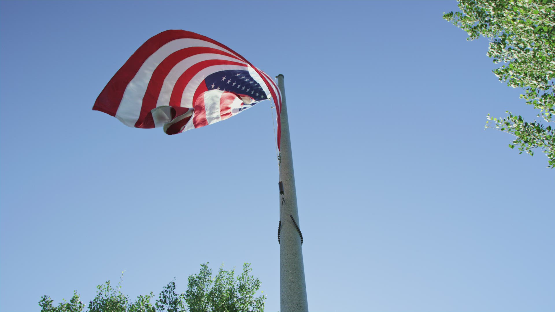 American flag waves against clear blue sky as seen from below looking up