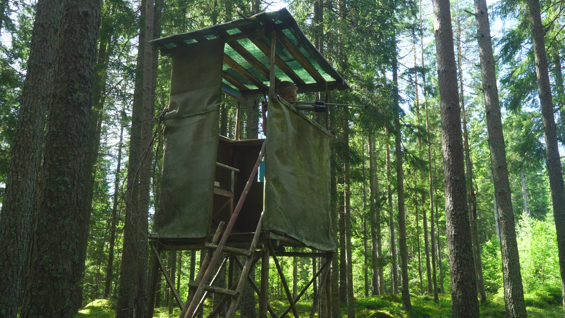 boy standing in hunting tower - playing - taking aim with tripod - target