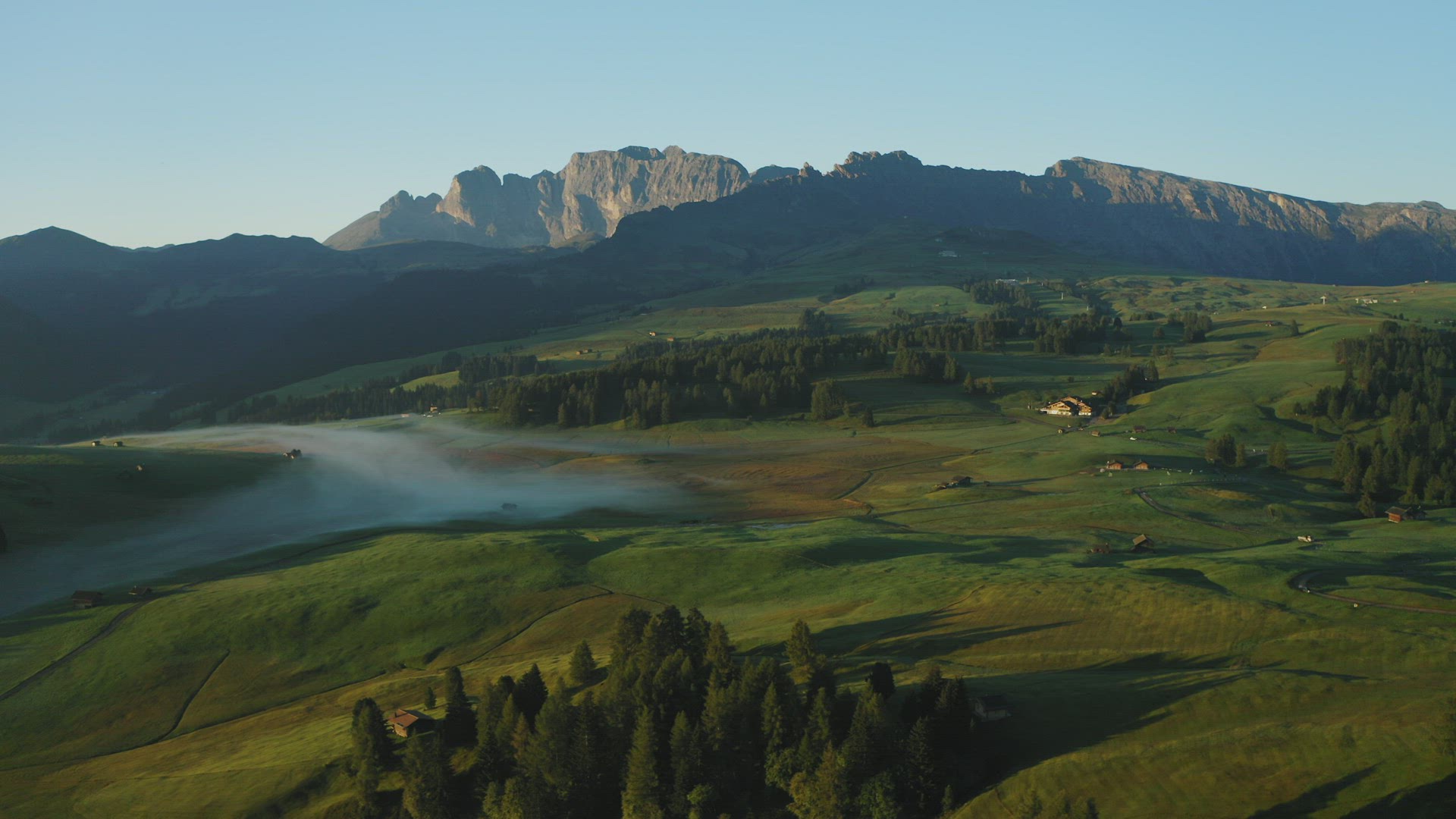 Sunrise on Seiser Alm with Schlern mountain of Rosengarten group in background and fog in the valley