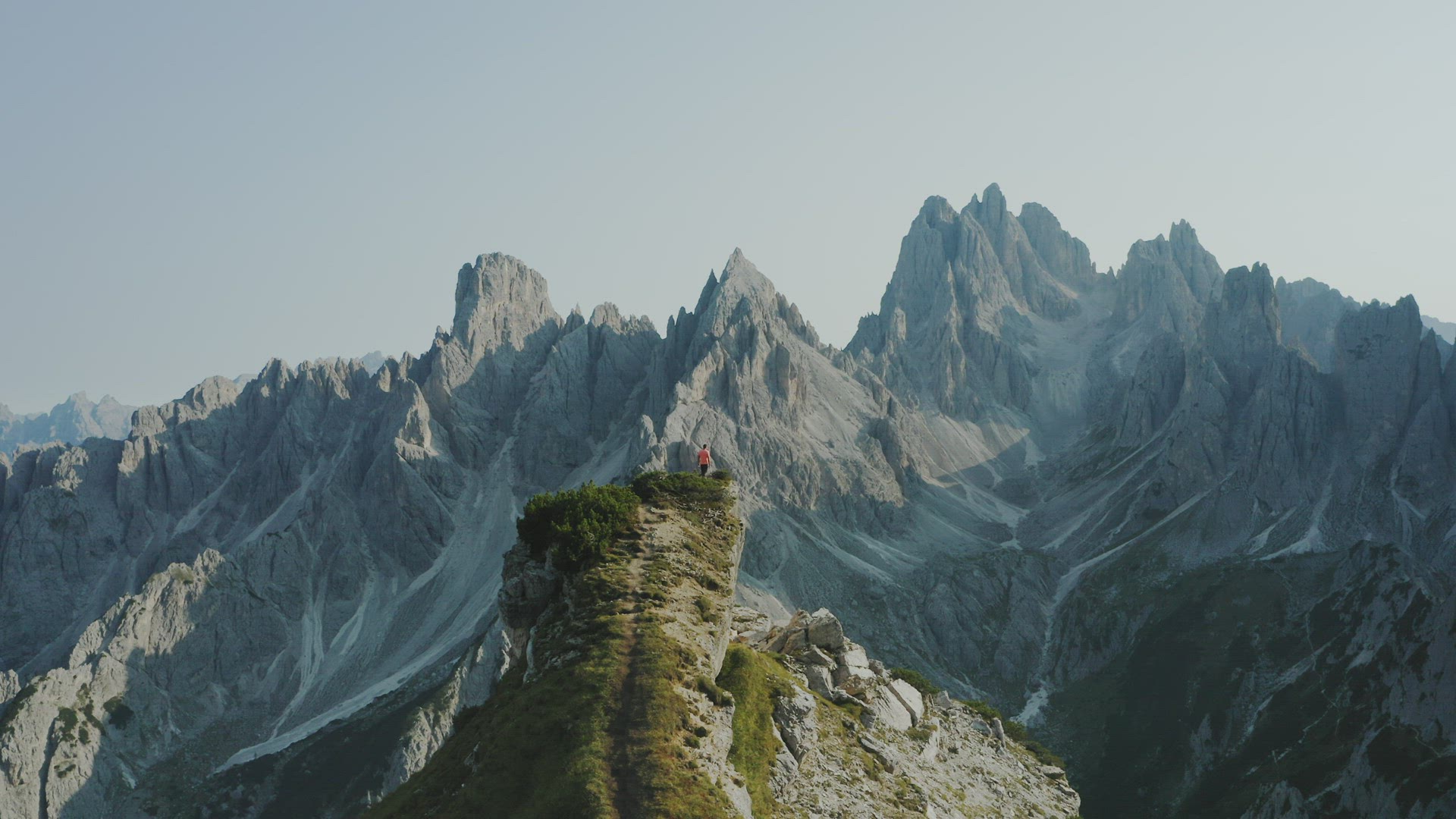 Dolomites, Italy. Man on mountain peak. Summit of Cadini di Misurina mountains group in background. 