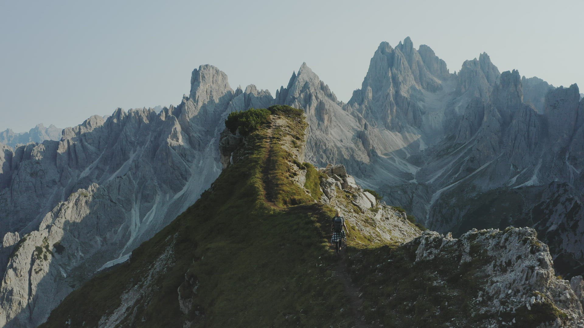 Women walks along cliff edge. The Cadini di Misurina mountains group in Dolomites, Italy in backgrou