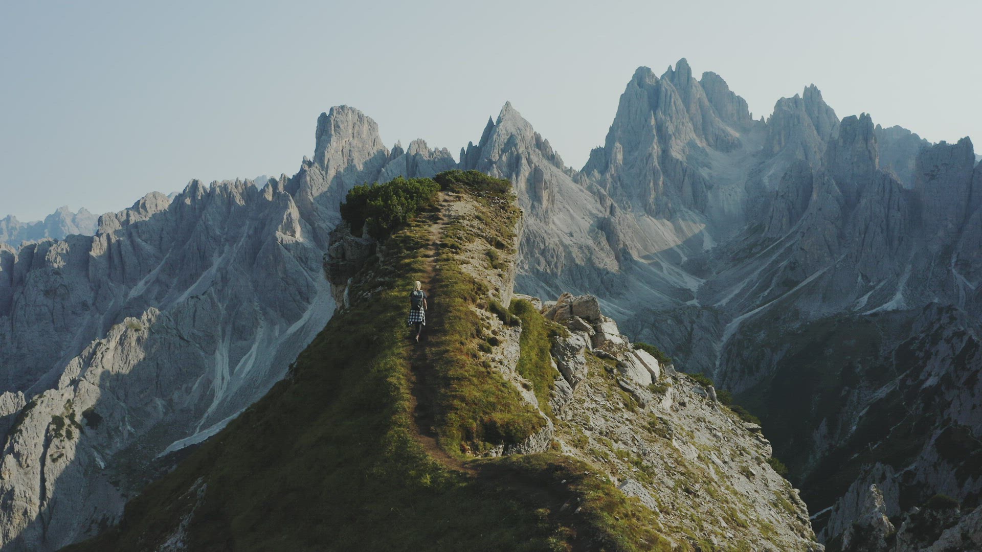Women walks on summit top rock. The Cadini di Misurina mountains group in Dolomites, Italy in backgr