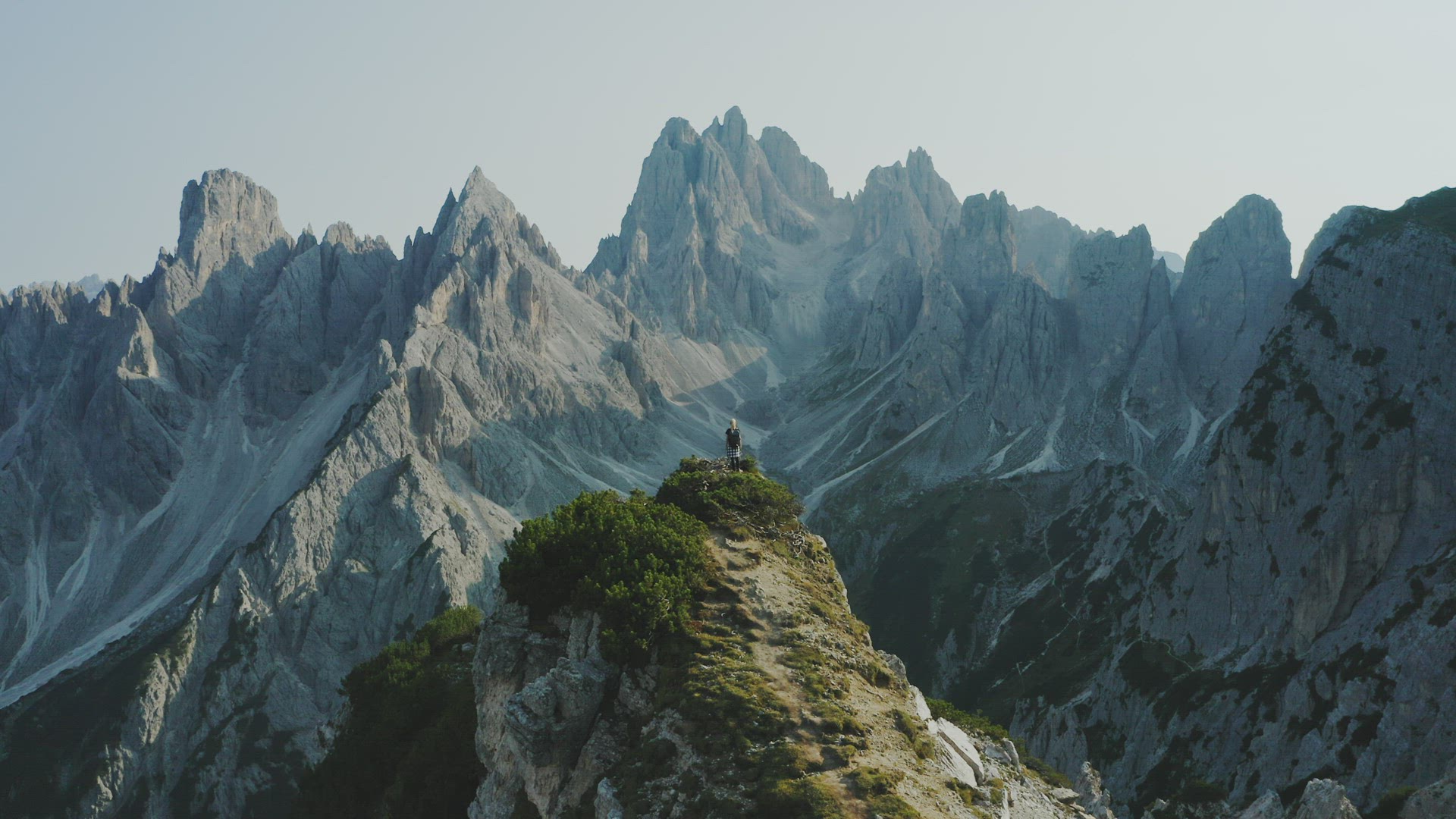 Women on cliff edge raising her hands. The Cadini di Misurina mountains group in Dolomites, Italy in