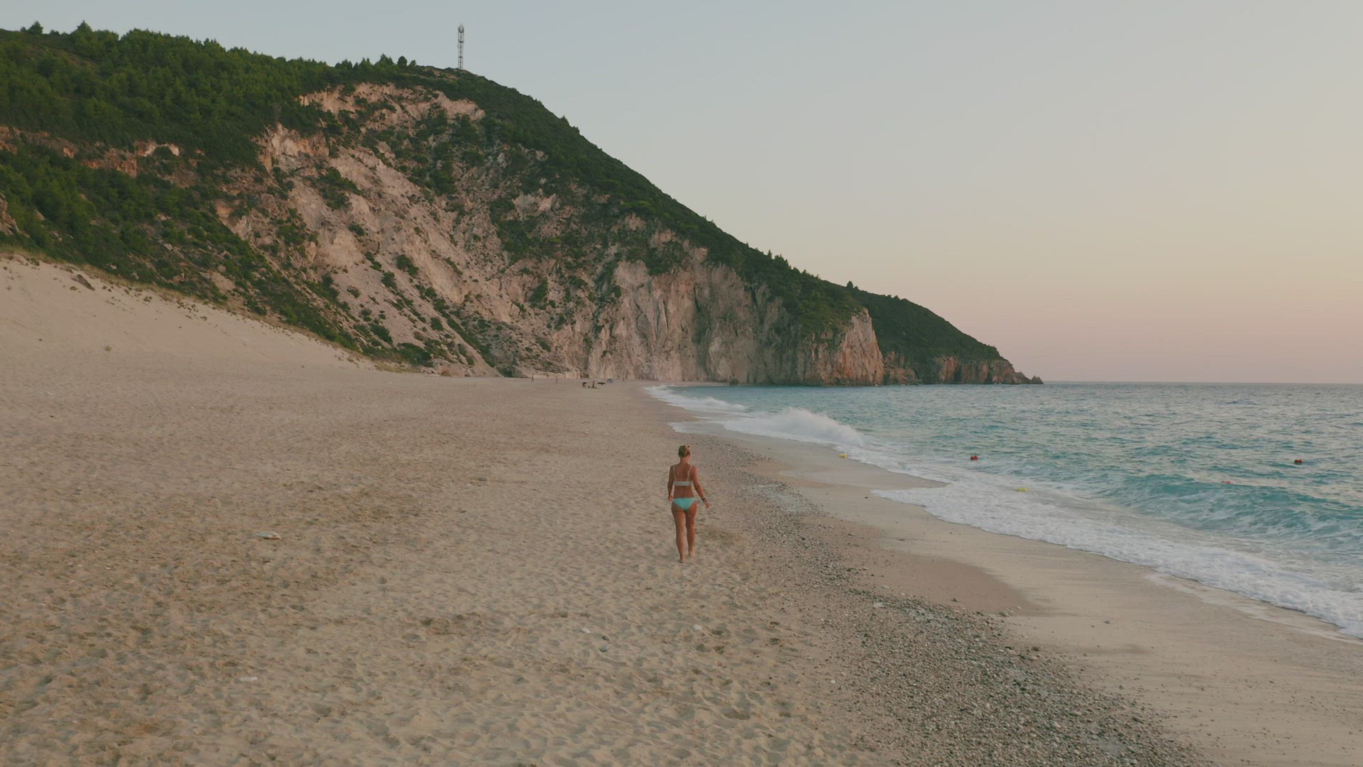 Aerial low altitude follow view of adult woman enjoying beautiful Milos beach of Lefkada, Ionian isl