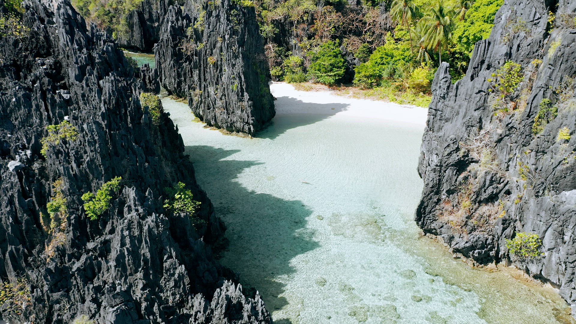 Aerial drone view over clear shallow lagoon water surrounded by sharp rocky formations. Hidden Beach