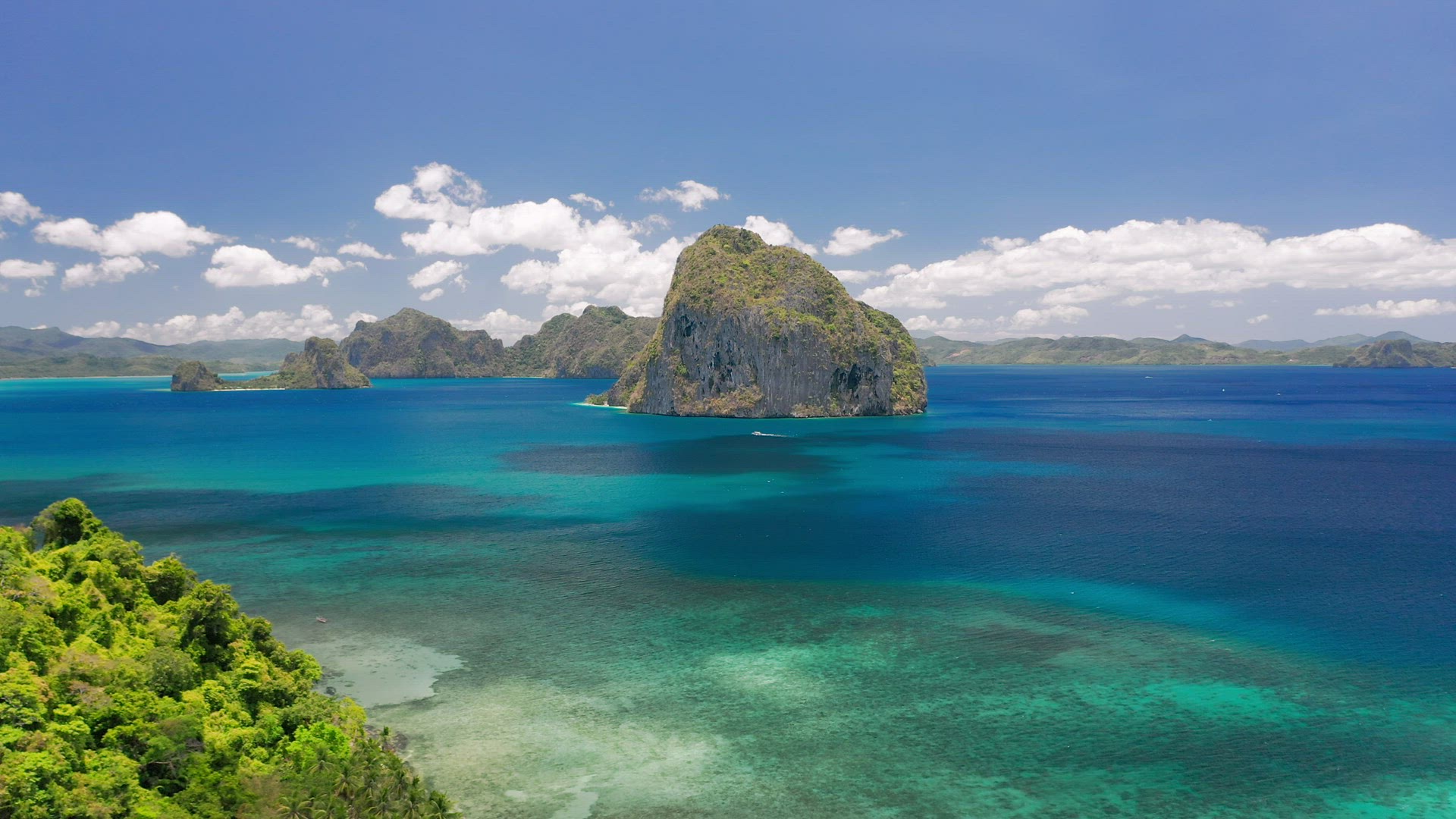 Aerial drone circling shot of rocky Pinagbuyutan island in open sea from the distance. El Nido, Pala