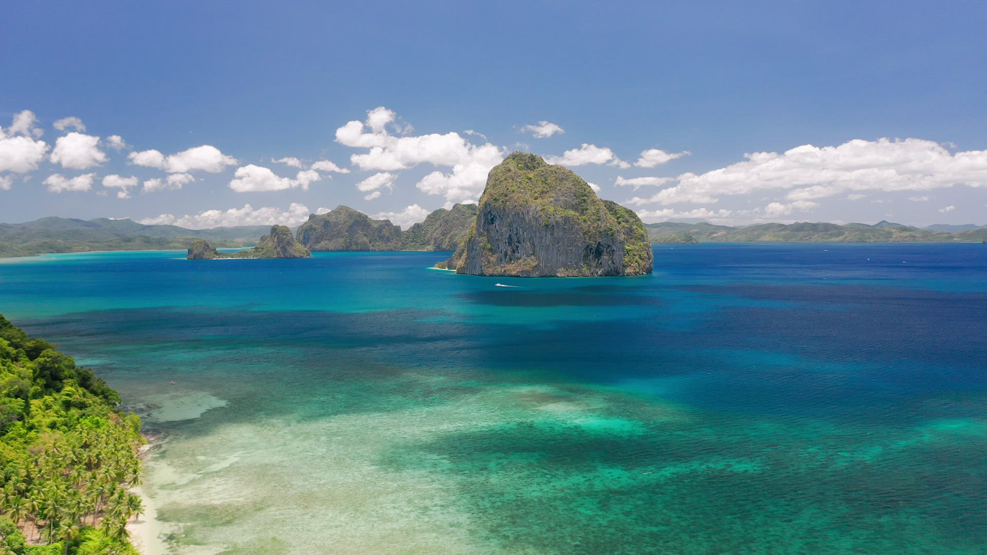 Aerial drone view of rocky Pinagbuyutan island in open sea from well-known Las Cabanas beach. El Nid
