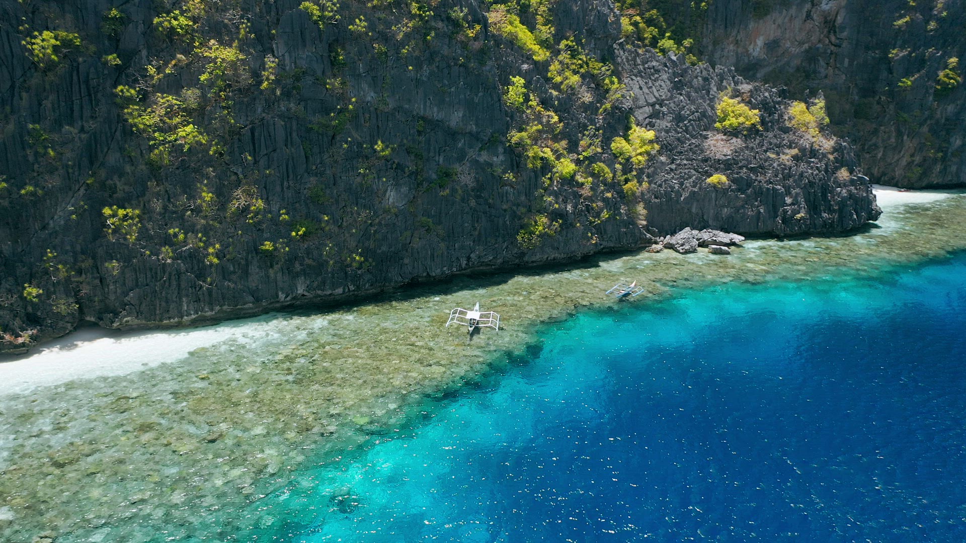 Aerial circling footage of tourist boats hover over coral reef near Matinlok shrine. El Nido, Palawa
