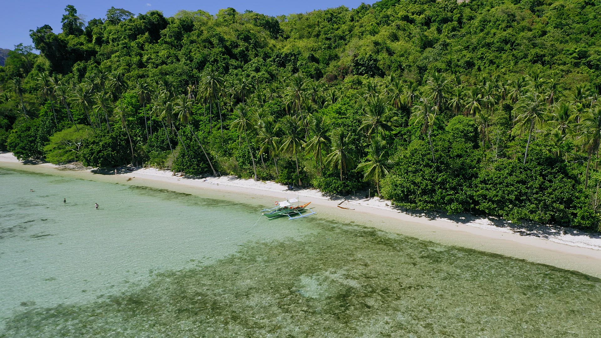 4k Aerial drone circle around banca boat at shallow clear water on paradise tropical beach surrounde