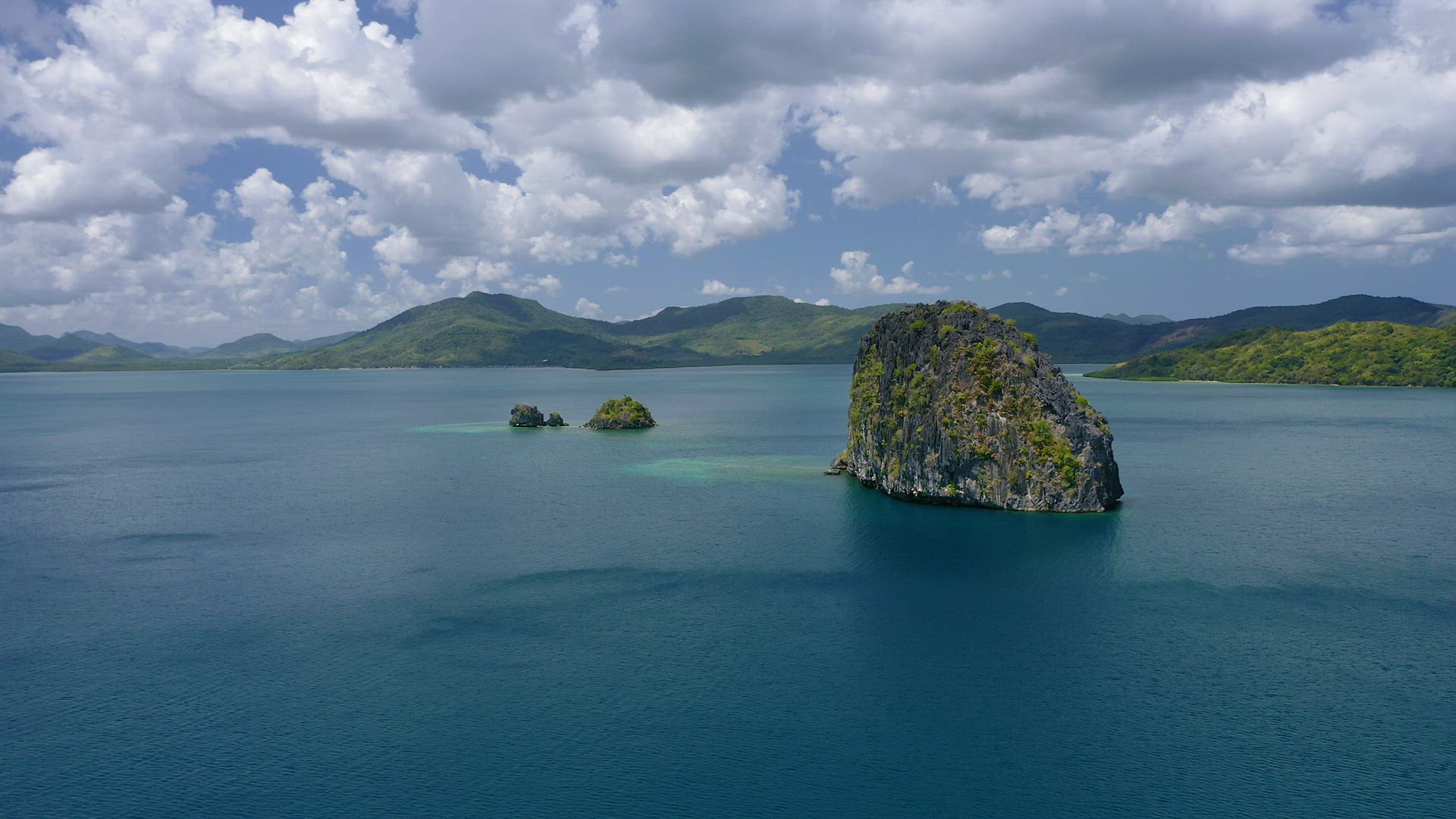 4k Aerial drone fly around isolated cliff rocks in ocean. Bacuit archipelago, El Nido. Palawan, Phil