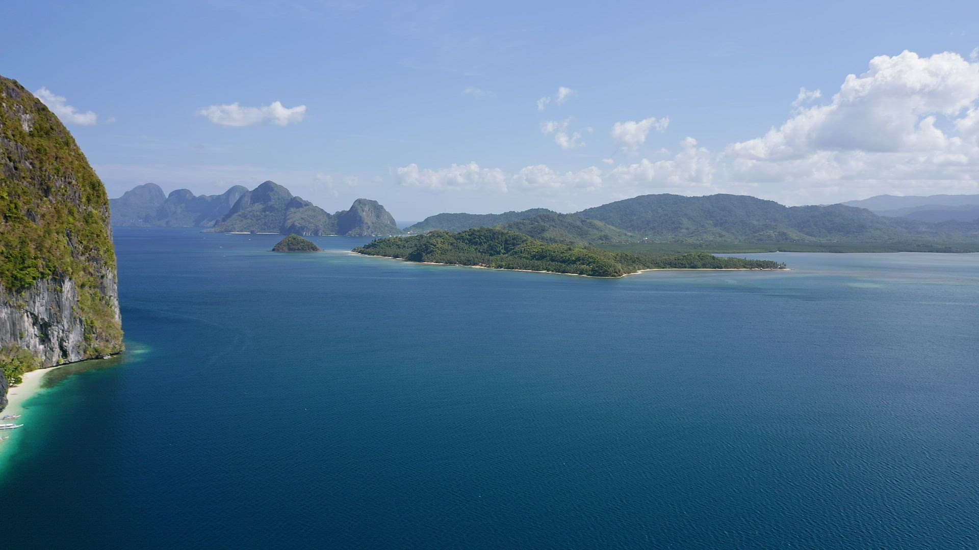 4K Aerial drone fly over ocean towards a El Nido mainland with towering limestone karst mountain rid