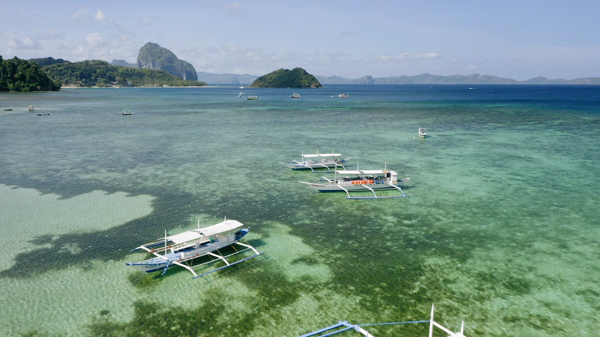 4K Aerial drone view of boats anchored in shallow water clear emerald green lagoon. Corong beach, El
