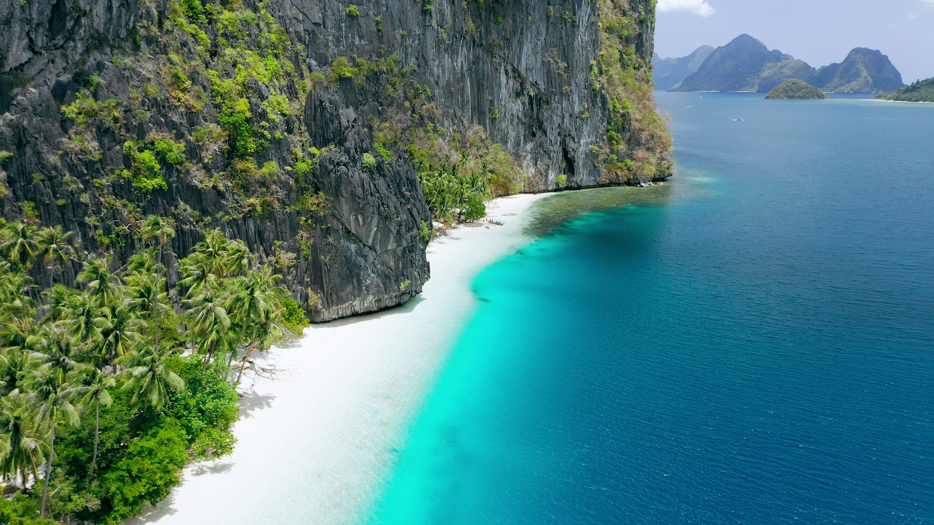Aerial drone view of pristine tropical white sand beach surrounded by karst rocky cliffs and turquoi