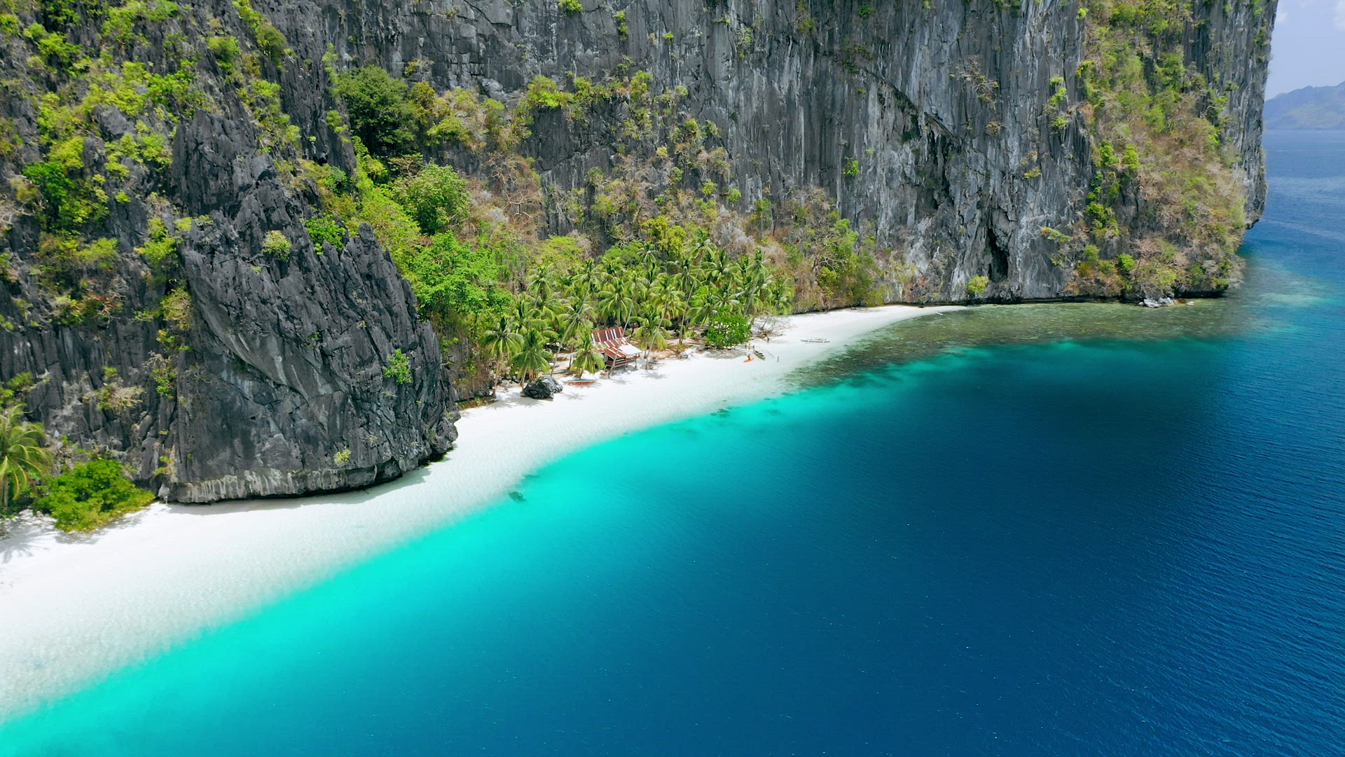 Aerial drone fly footage of pristine tropical white sand beach surrounded by karst rocky cliffs and 