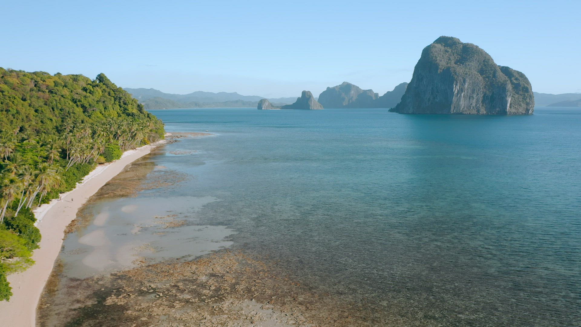 Aerial drone panoramic view of El Nido coastline at the low tide. Long Sandy beach and palm trees. E