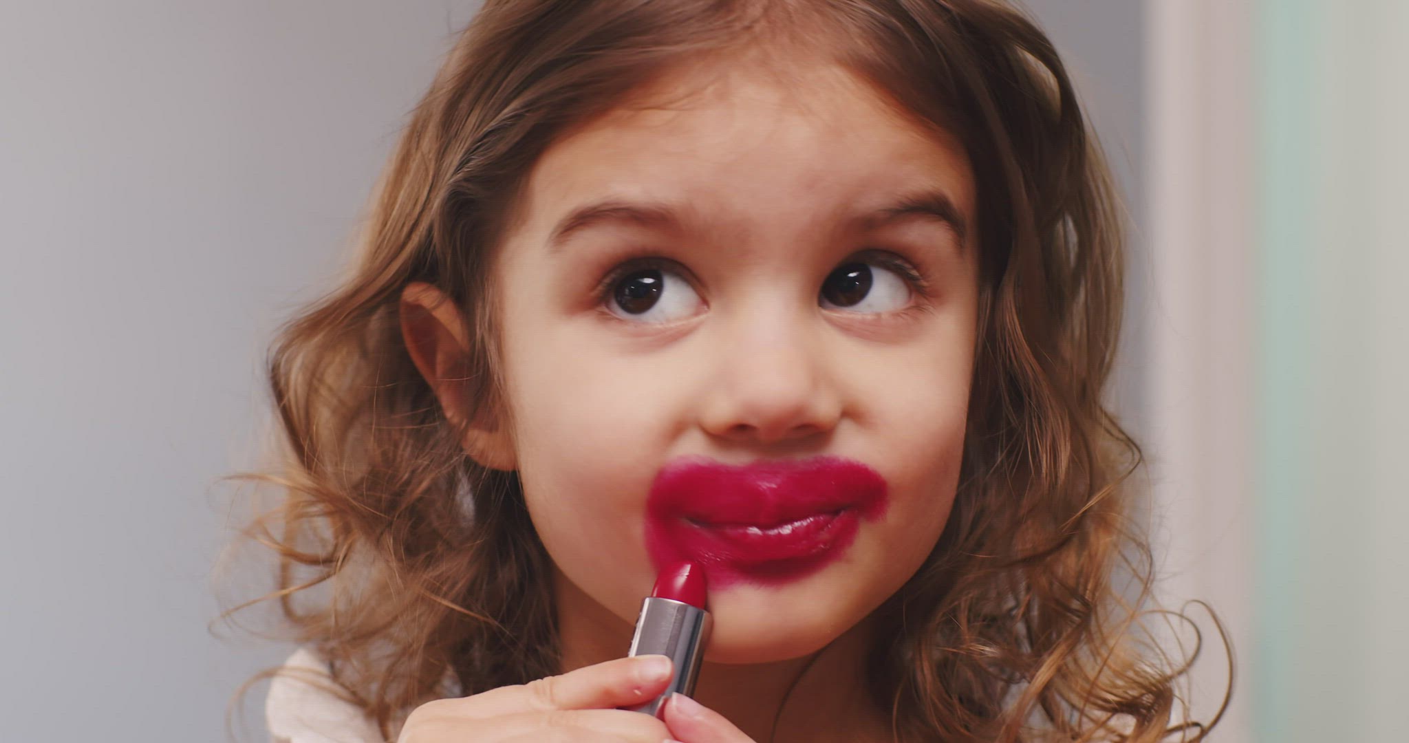 Cute toddler girl trying on lipstick for the first time.
