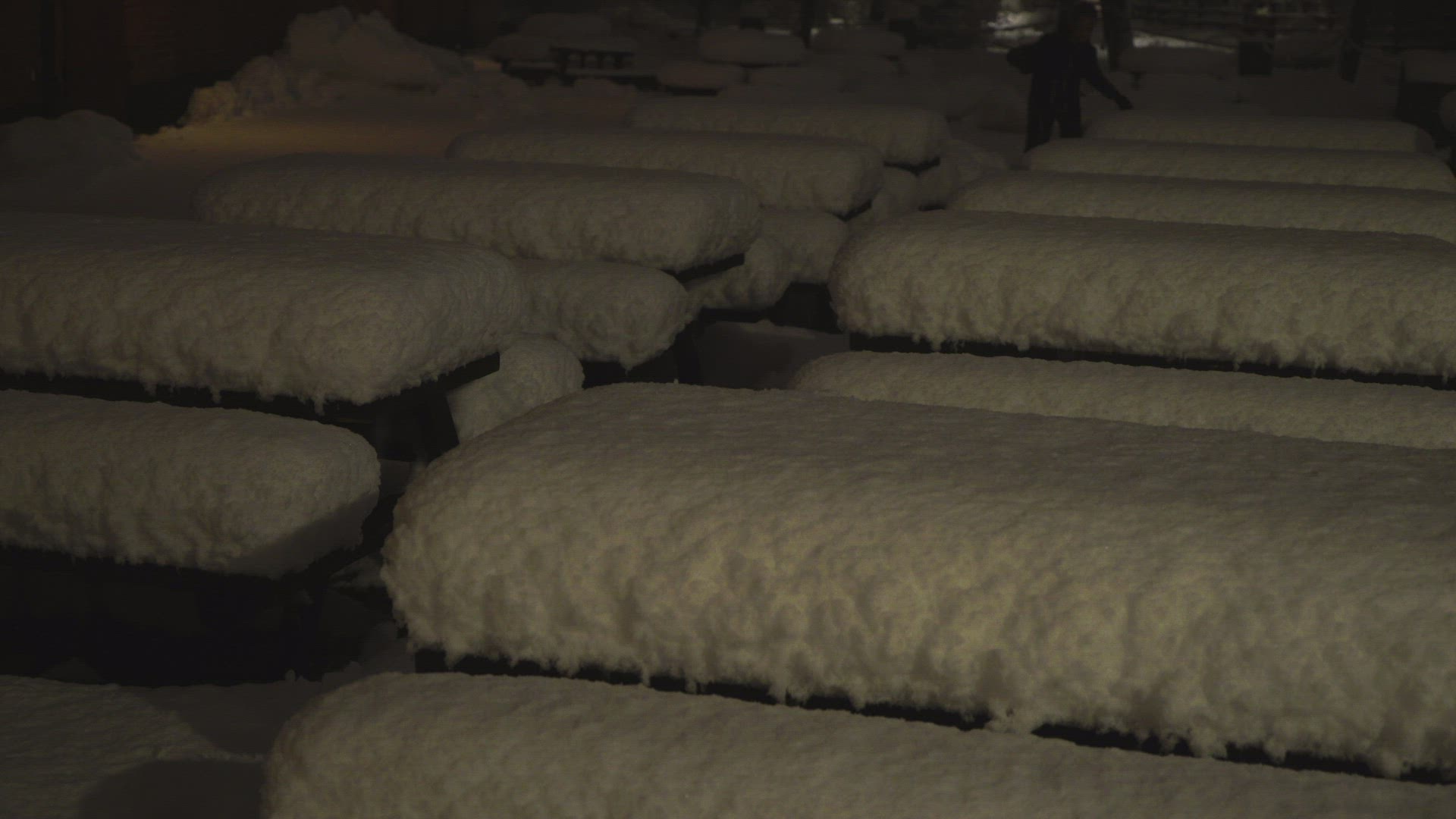 evening night shot - boy walking through snowcovered tables at outdoor restaurant