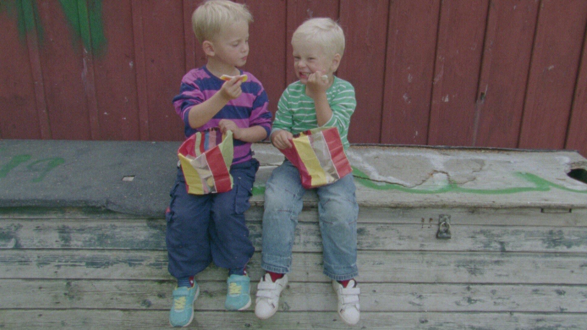 two boys eating candy - sitting on bench