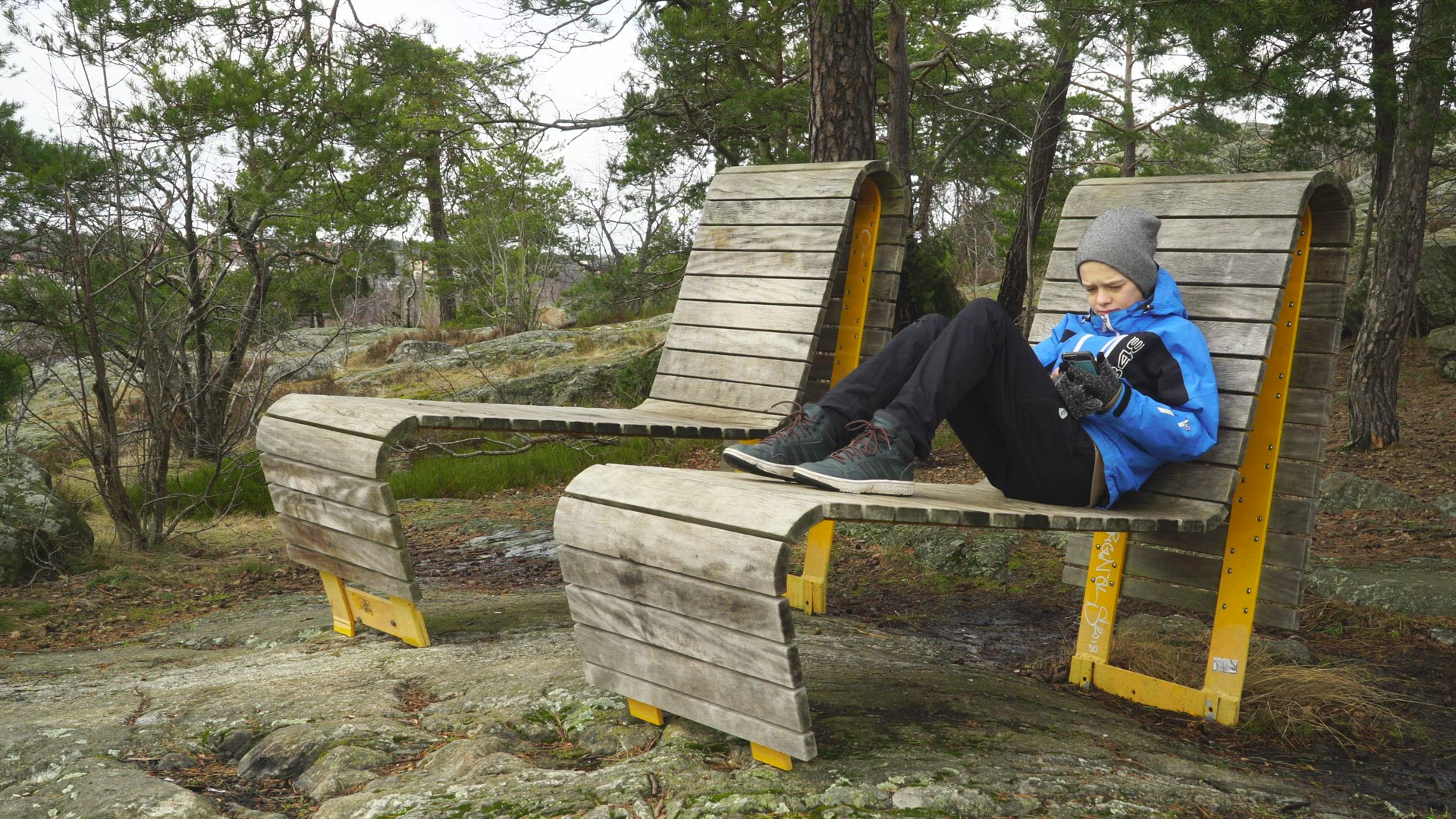 boy sitting in large chair at viewpoint - using mobile phone