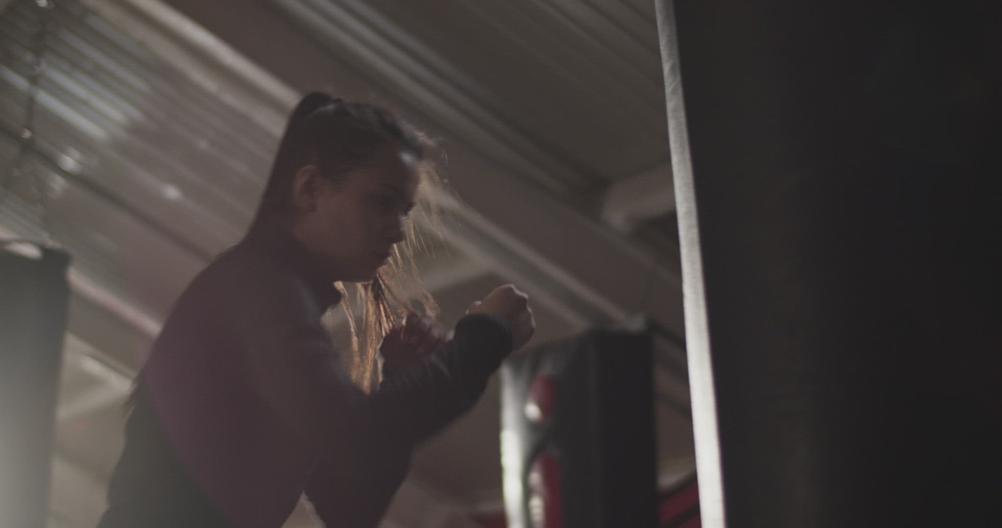 Strong female boxer punching bag  