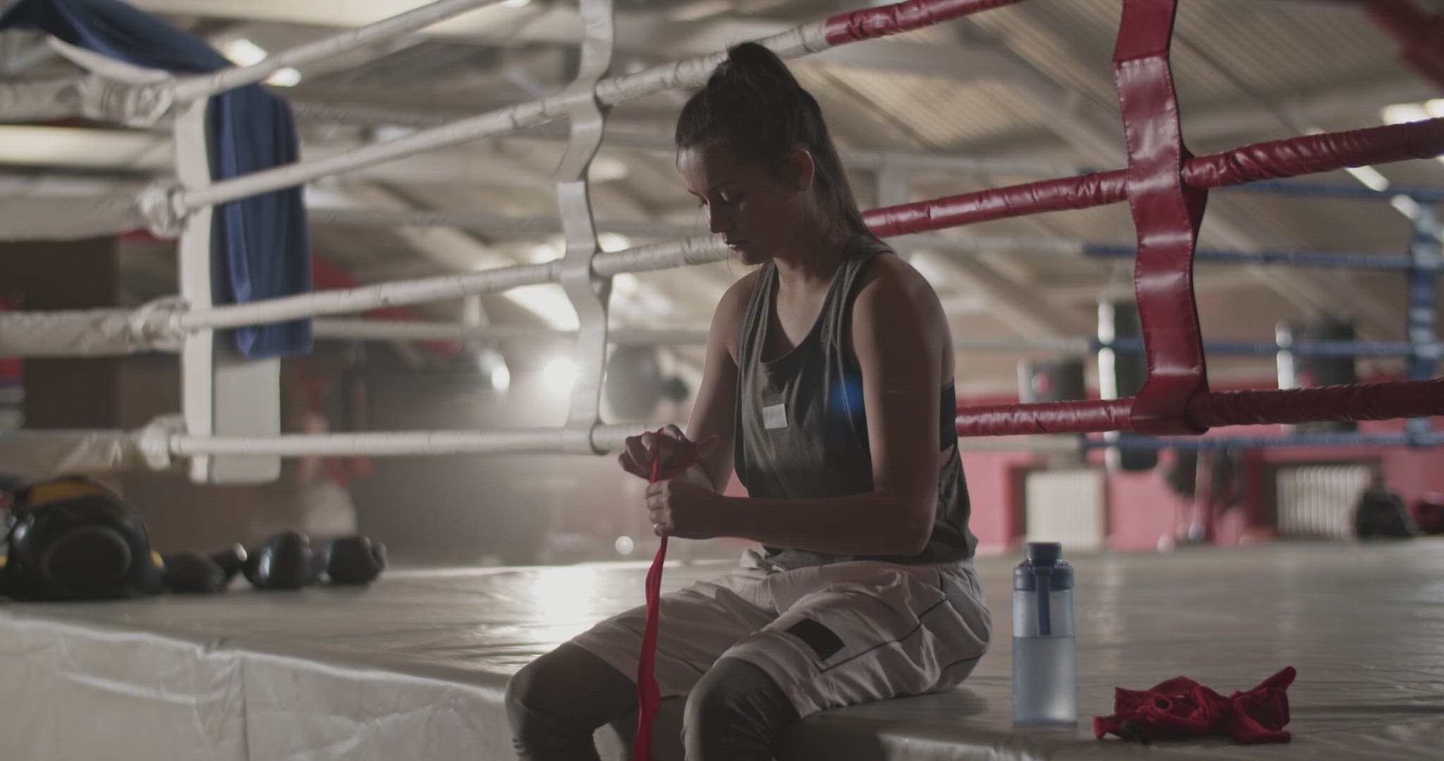 Female boxer bandaging hand near ring