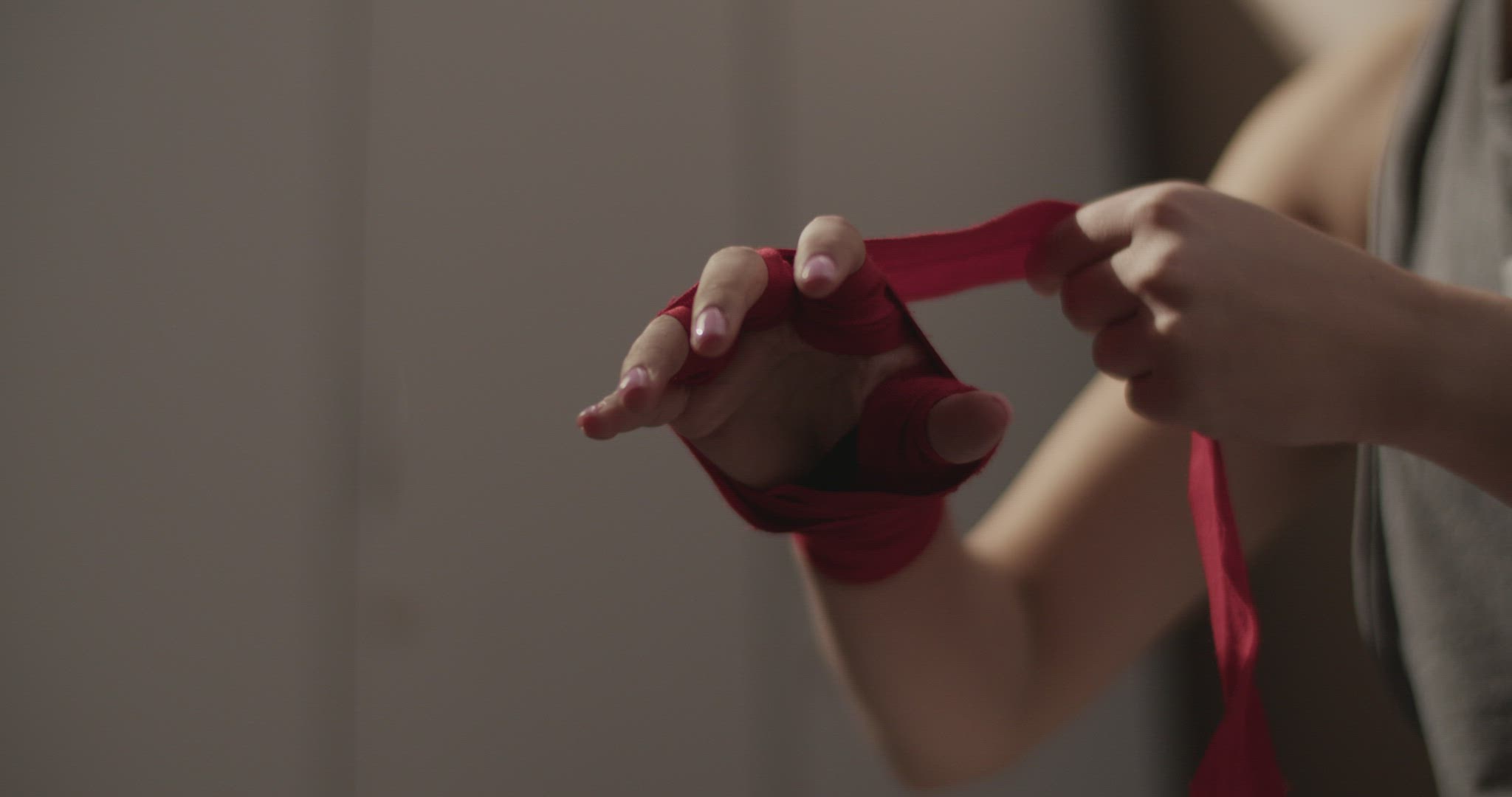 Crop sportswoman unwrapping red bandage